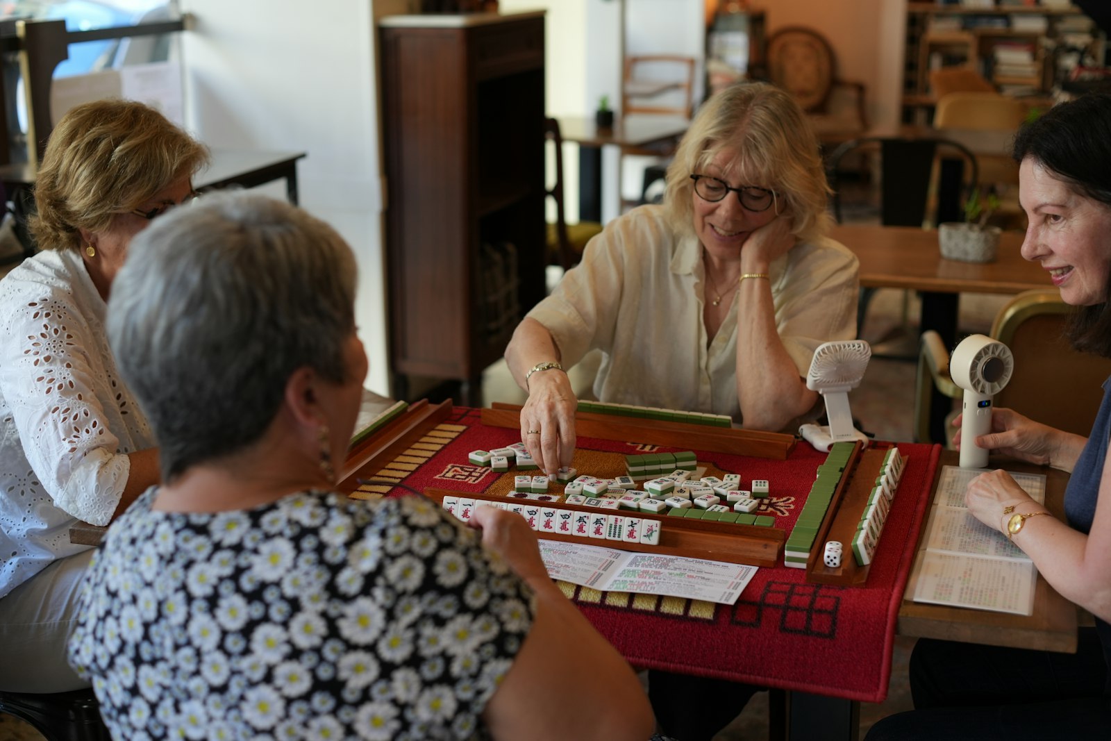 Friends playing American mahjong with racks at a table