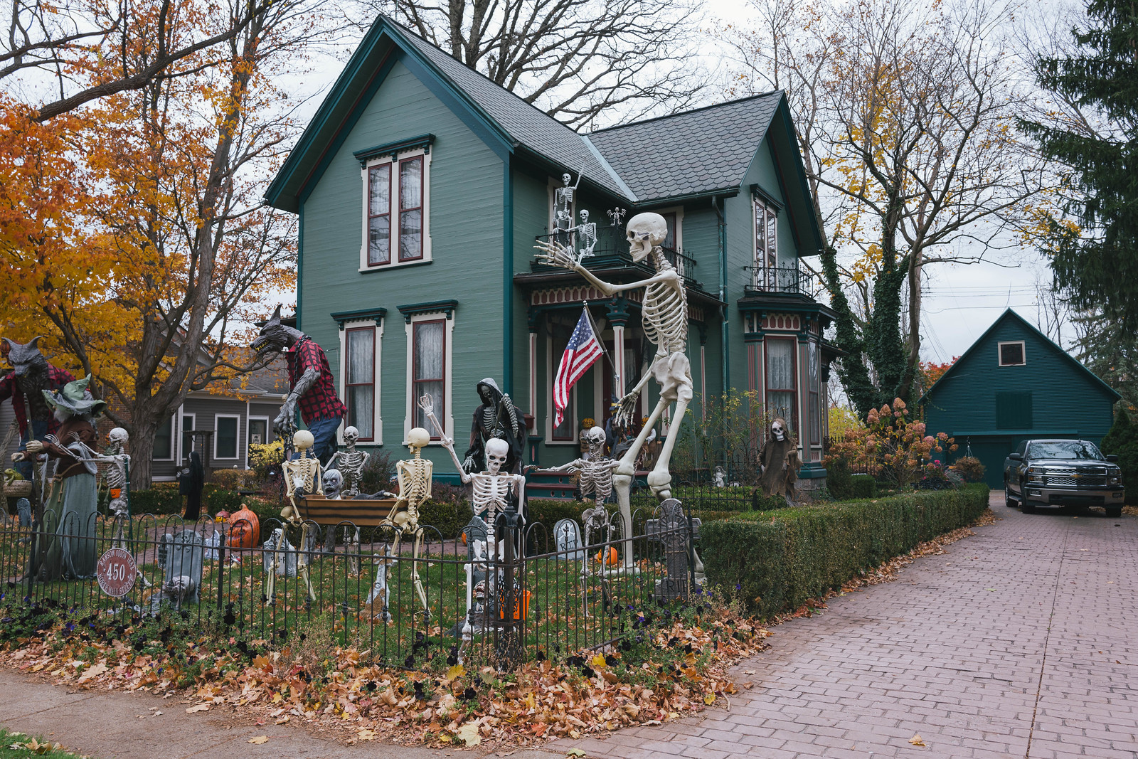 Green Victorian house in Romeo, Michigan, with a giant skeleton and Halloween yard display