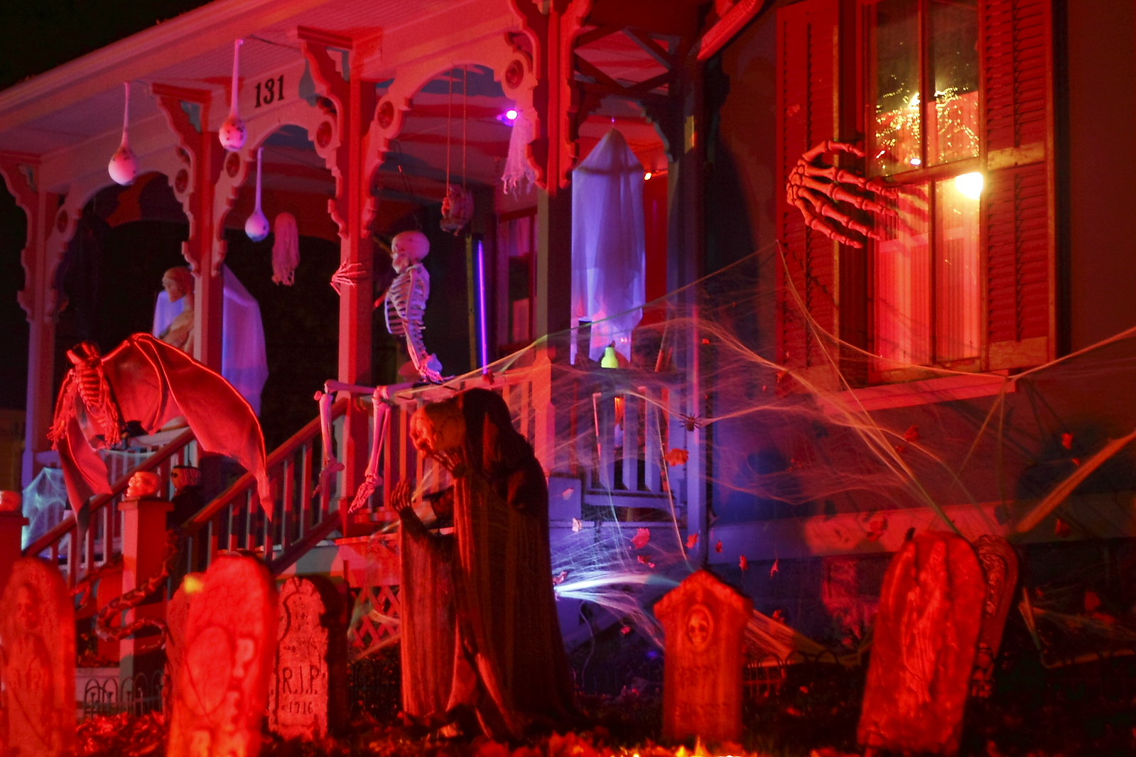 Metro Detroit Halloween streets: a Victorian porch on Tillson Street in Romeo decorated with skeletons, tombstones and cobwebs under red lights